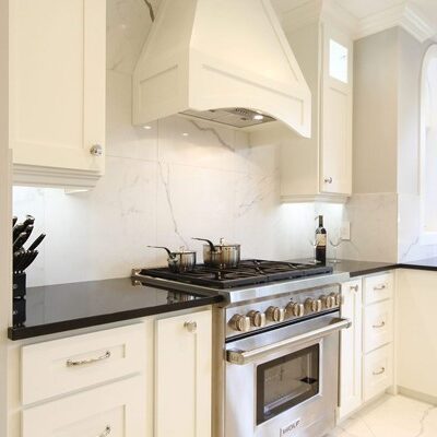 A kitchen with white cabinets and black counter tops.